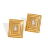 Pair of gold-framed earrings with clear gemstones on a white background