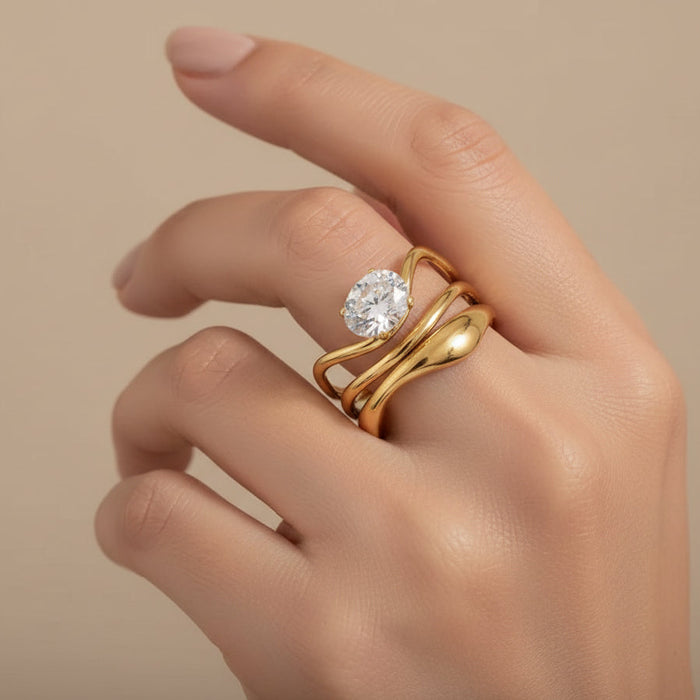 Gold ring with a diamond on a hand against a beige background